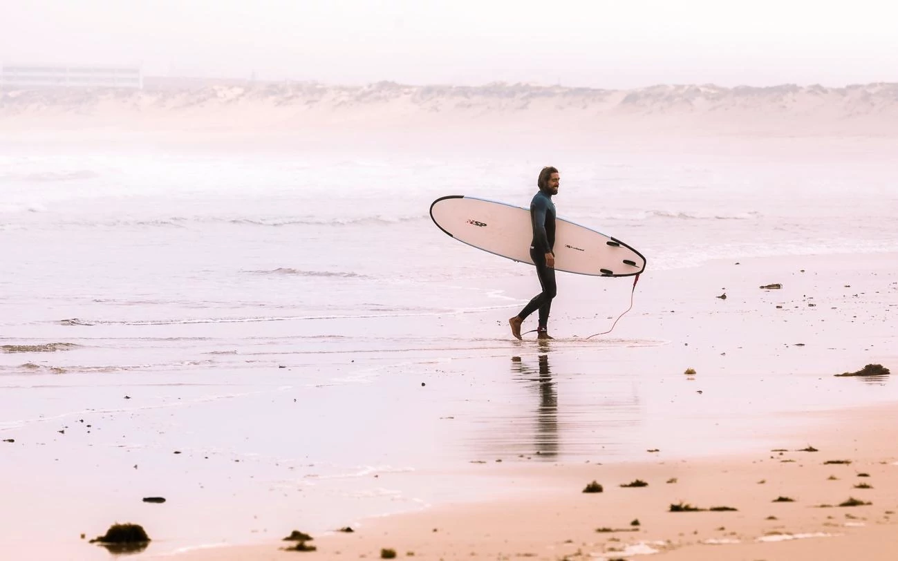 turista en la playa con su tabla de surf